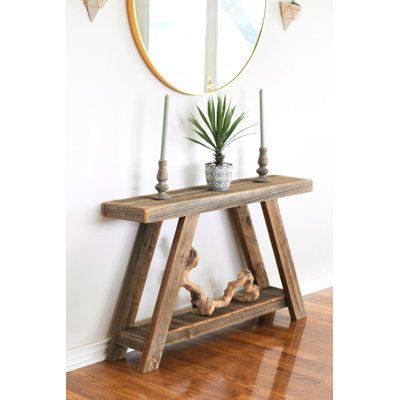 a wooden table with a plant on it and a mirror above it in a room