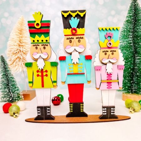 three wooden nutcrackers standing next to each other in front of christmas trees