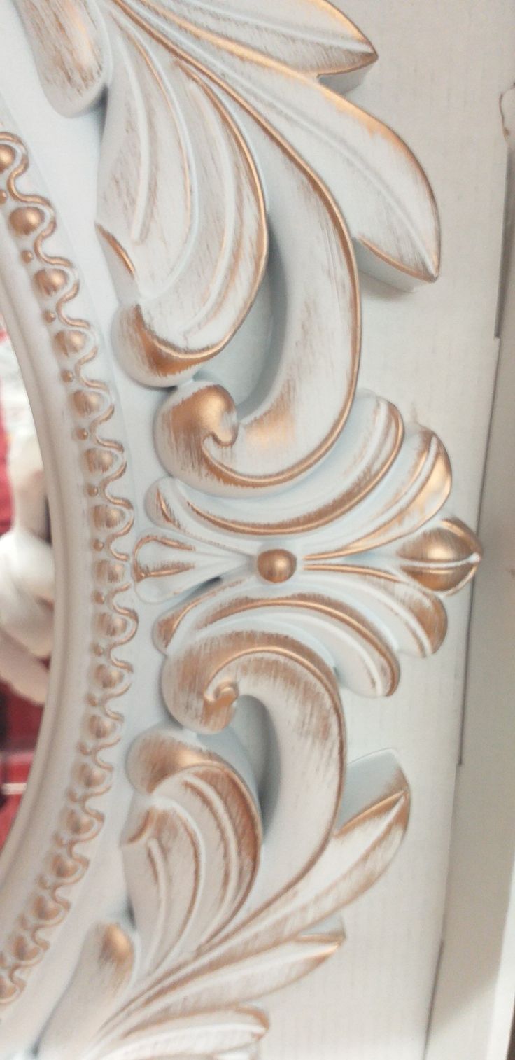 an ornate white and gold mirror on the wall