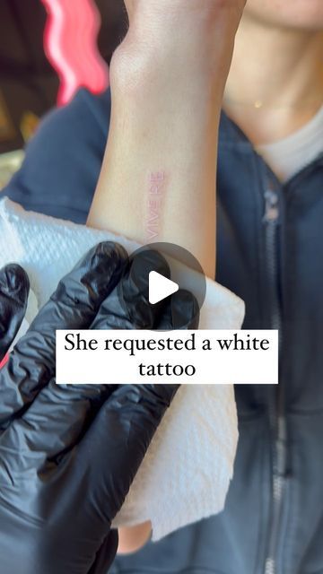 a woman wearing black gloves and holding up her wrist with the words she requested a white tattoo on it