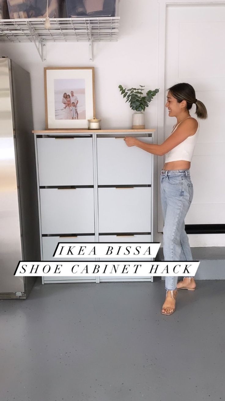 a woman standing in front of a refrigerator freezer next to a shelf with pictures on it