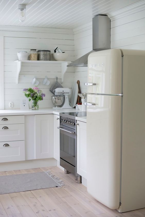 a kitchen with white walls and wooden floors has an oven, refrigerator, dishwasher and stove