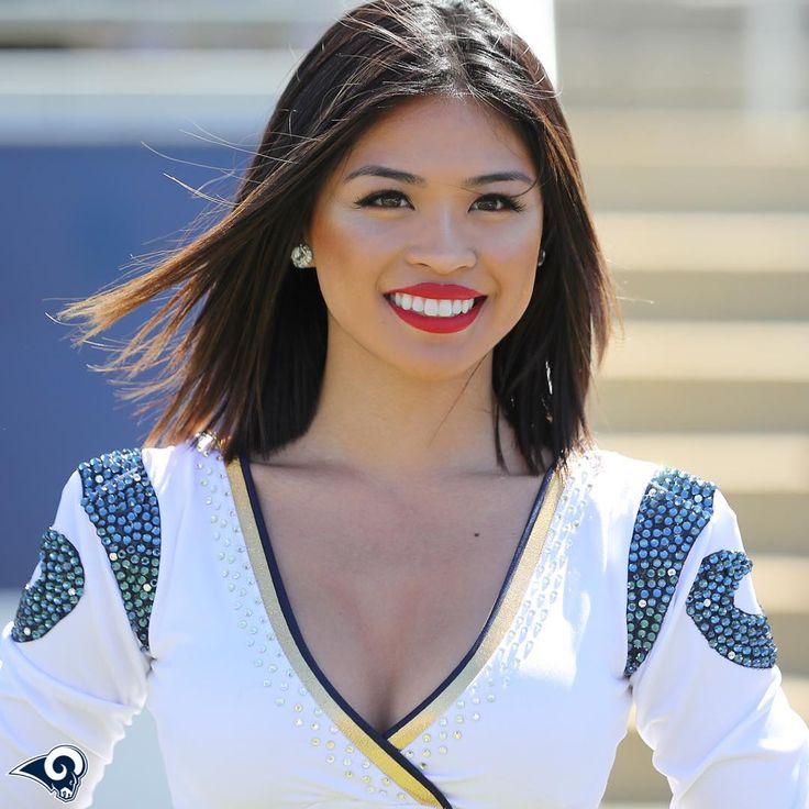 a woman in white and blue dress with red lipstick on her lips smiling at the camera