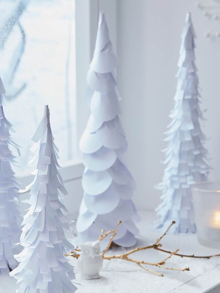 white paper christmas trees sitting on top of a counter next to a window sill