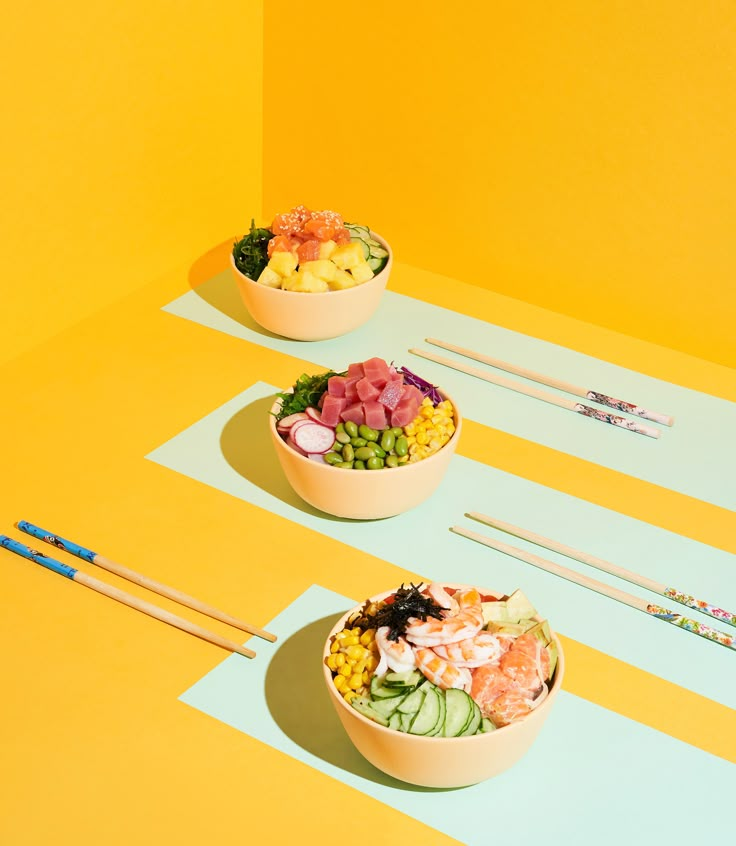 three bowls filled with different types of food and chopsticks next to each other