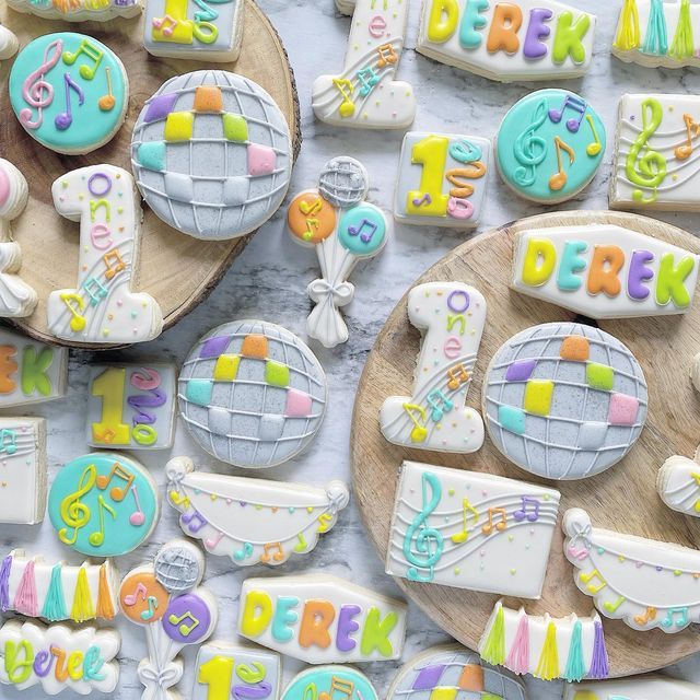 decorated cookies on wooden platters with letters and music notes in the middle, along with other cookie decorations