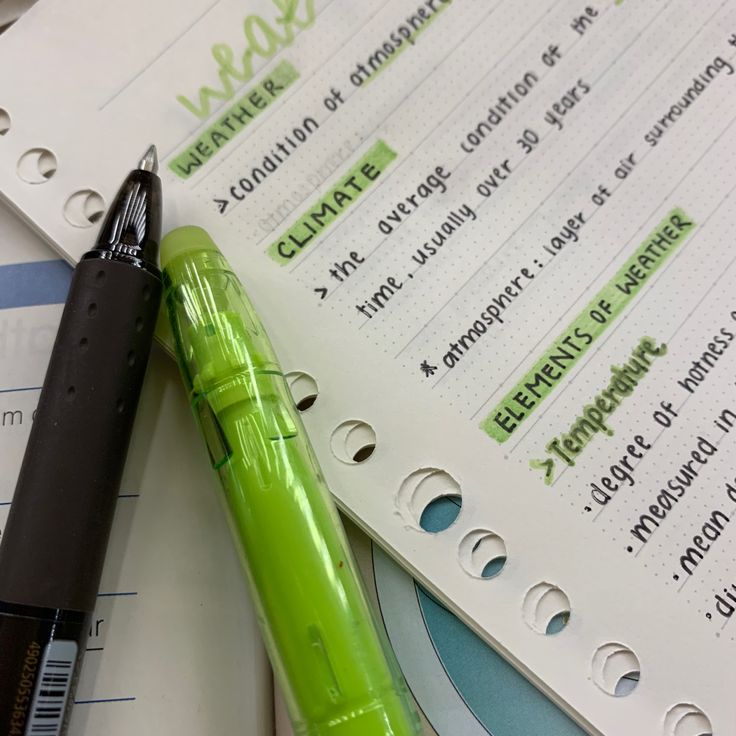 a green pen sitting on top of a paper