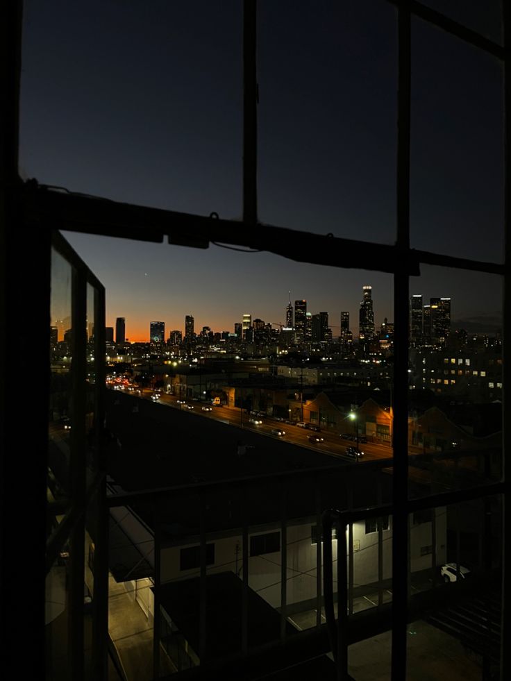 the city lights are shining brightly in the dark night sky from an apartment building's window