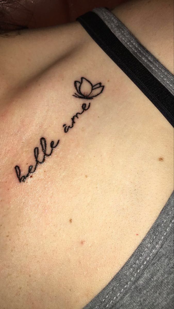 a woman's chest with the words believe and a lotus tattoo on her left side