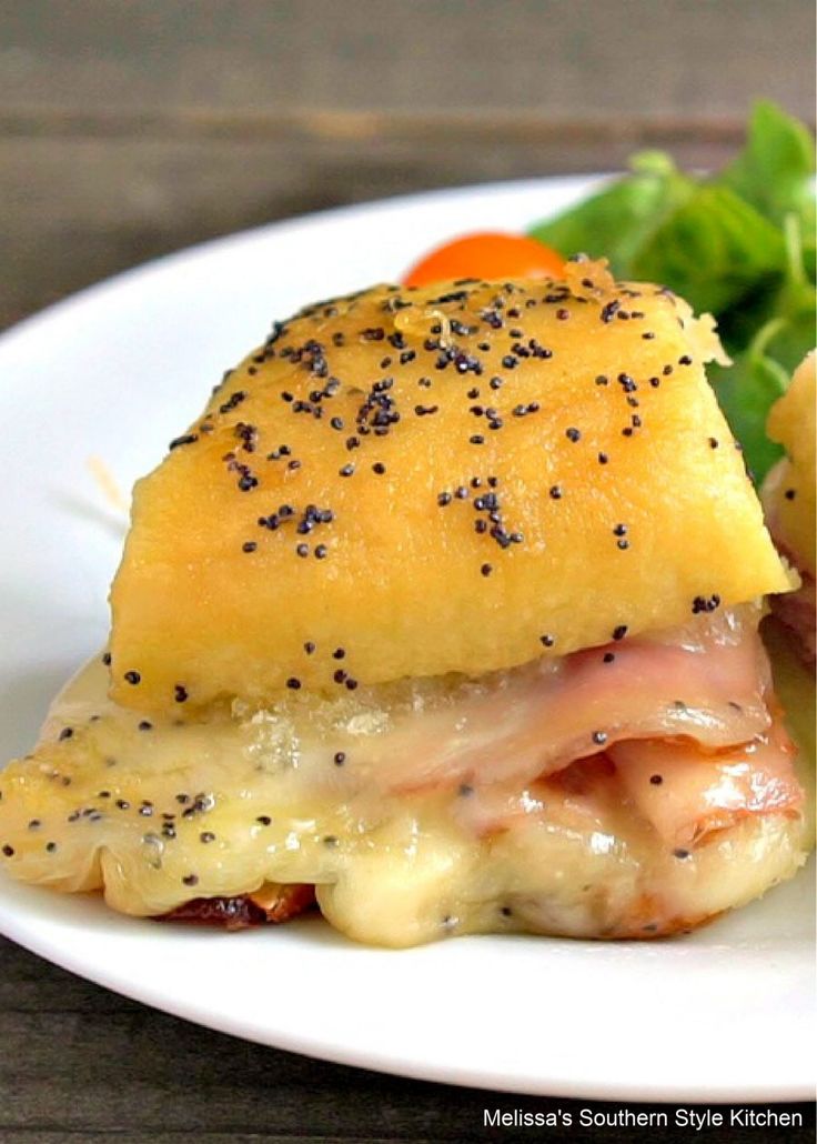 a white plate topped with ham and cheese covered in seasoning next to a salad