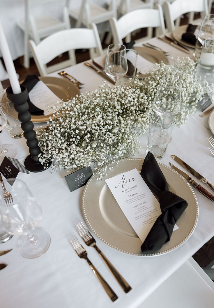 a table set with place settings, silverware and baby's breath centerpieces