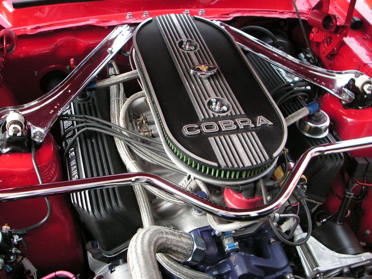 the engine compartment of a red car with an cobra logo on it's hood