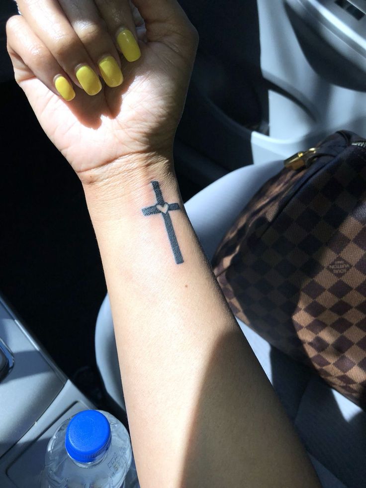 a woman's arm with a cross tattoo on it