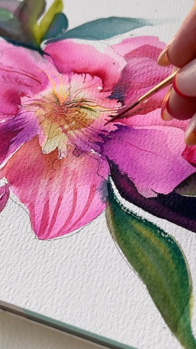 a person is painting a flower with watercolors