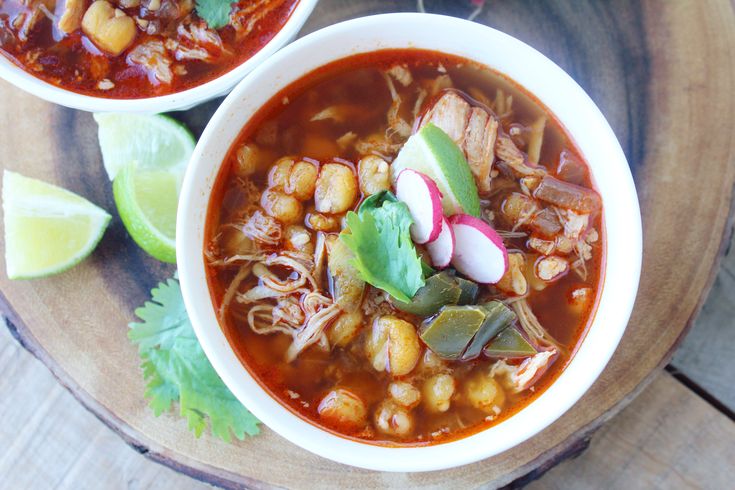 two bowls filled with soup and garnished with cilantro, lime wedges