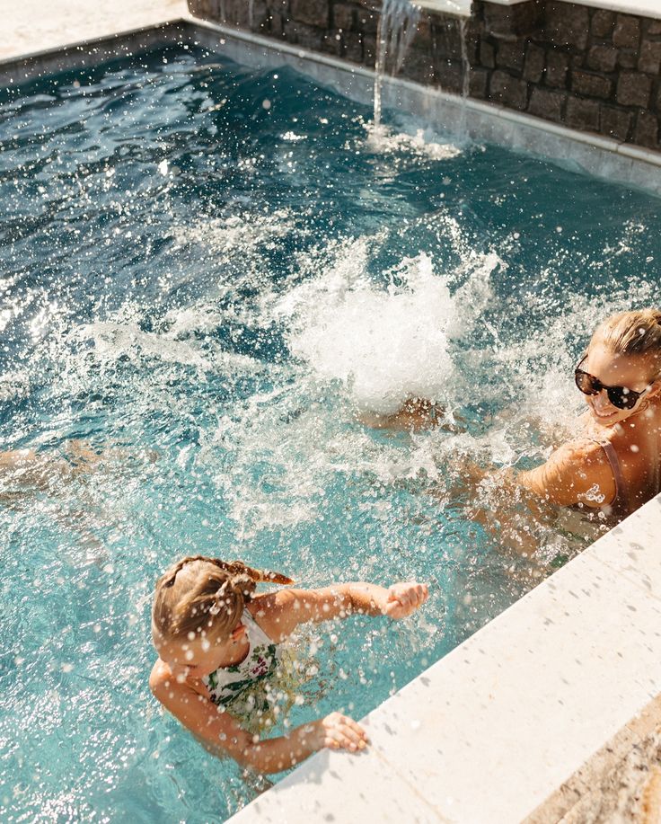 two people are playing in the pool with water