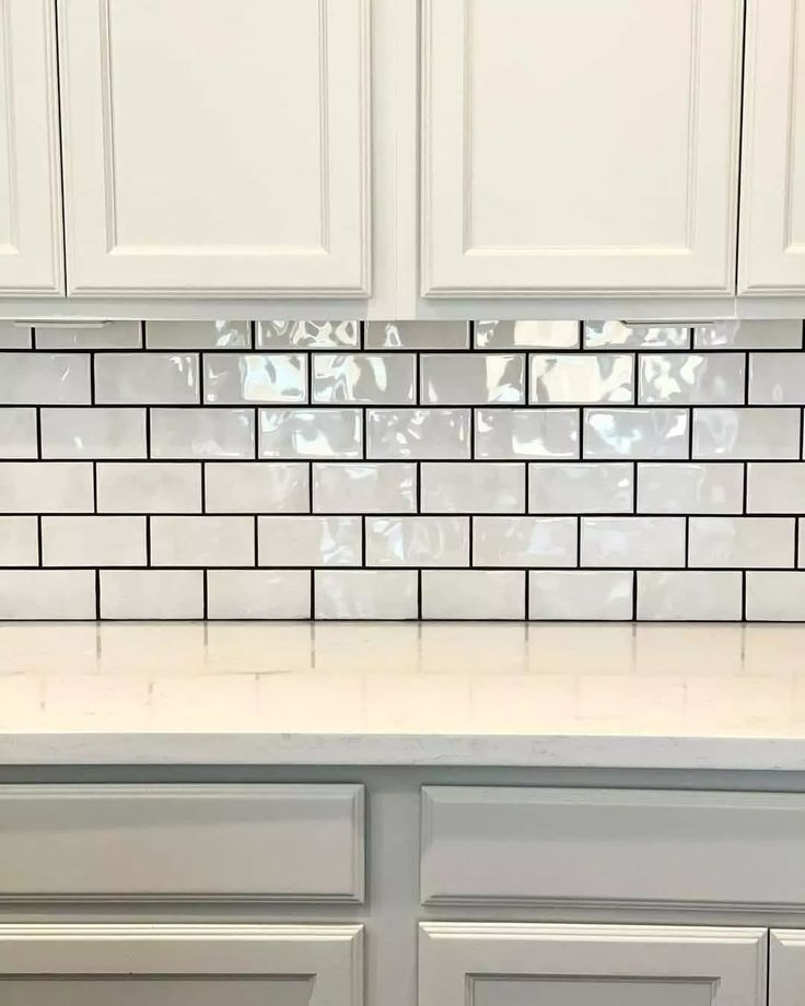 a kitchen counter with white cabinets and tile backsplash