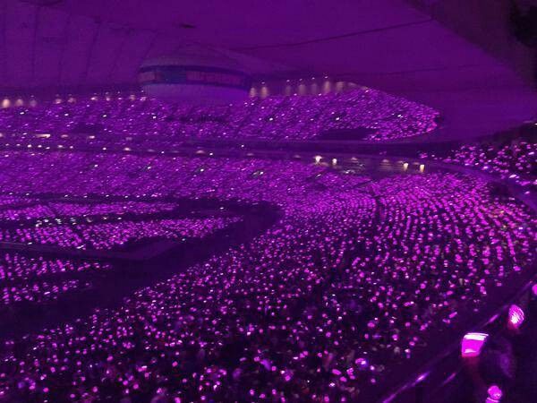 a large crowd of people sitting in the middle of a room filled with purple lights