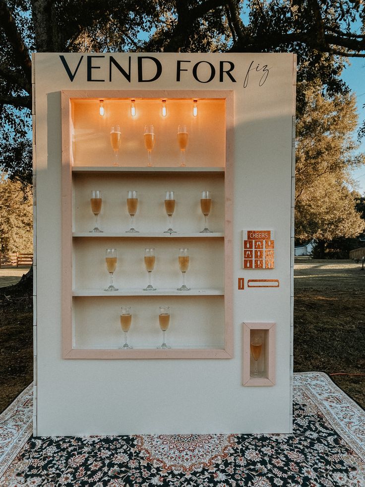 a display case filled with wine glasses on top of a carpeted floor next to trees