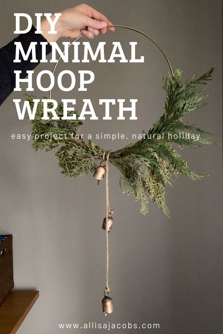 a hand holding a small hoop with pine cones and bells hanging from it's side