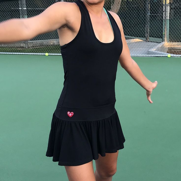 a woman in a black tennis dress holding a racquet on a tennis court