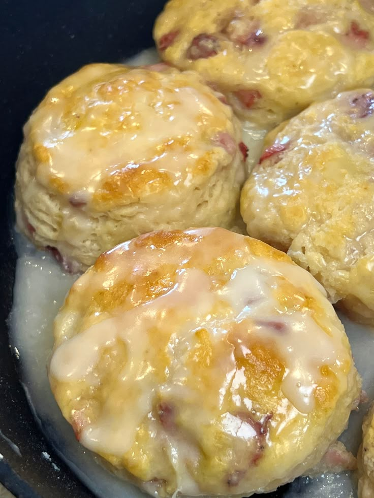 biscuits are being cooked in a skillet with melted cheese and jelly toppings on top