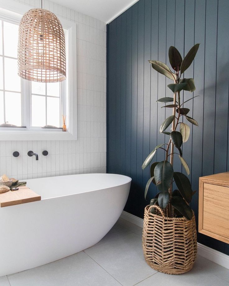 a white bath tub sitting next to a wooden cabinet in a blue and white bathroom