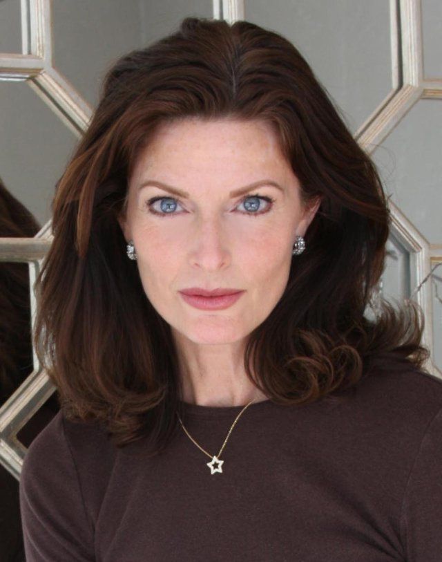 a woman with blue eyes wearing a brown shirt