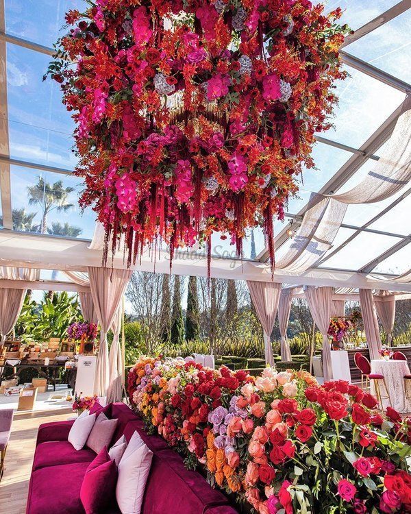 a room filled with purple couches and lots of flowers hanging from it's ceiling