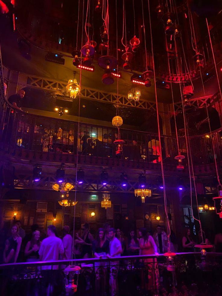 a group of people standing in front of a building with lights hanging from the ceiling