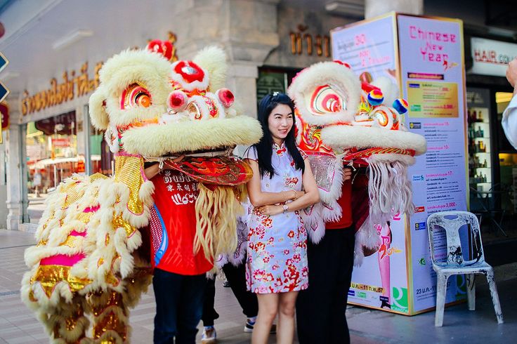 a woman standing next to two lion dancers