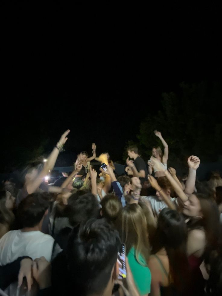 a group of people standing around each other with their arms in the air and one person holding up his cell phone