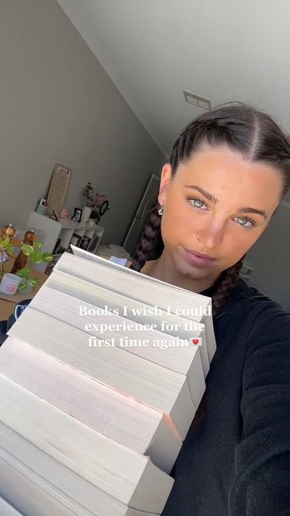 a woman holding a stack of books in front of her face