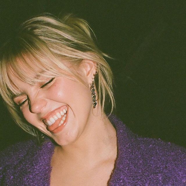 a woman laughing while wearing a purple sweater