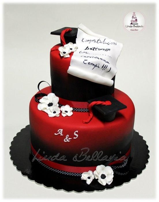 a red and black graduation cake with white flowers