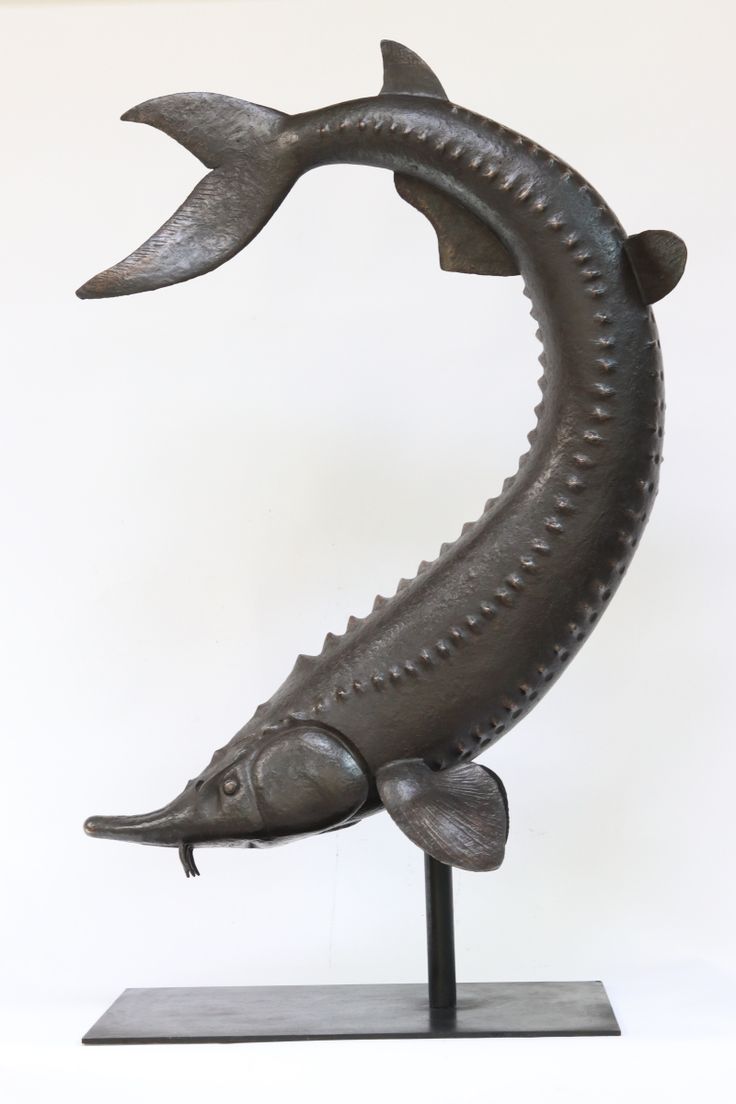 a metal sculpture of a fish on a stand