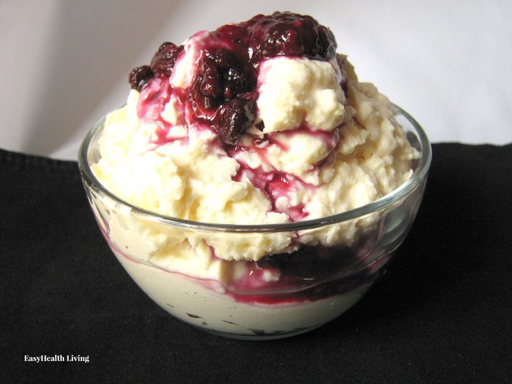 a glass bowl filled with ice cream and cranberry sauce on top of a black table