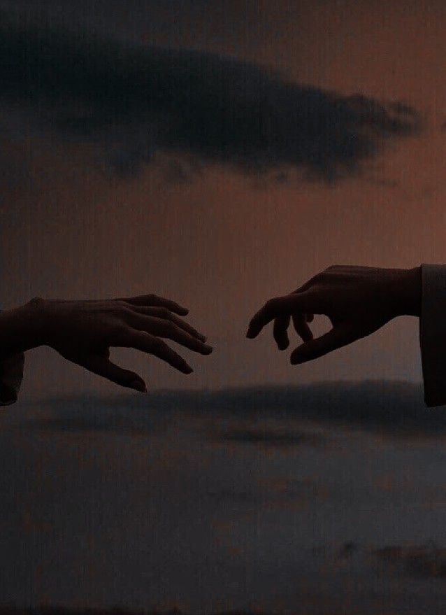 two hands reaching out towards each other in front of a dark sky with clouds and the sun behind them