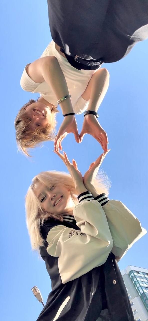 two women standing in the shape of a heart with their hands on top of each other