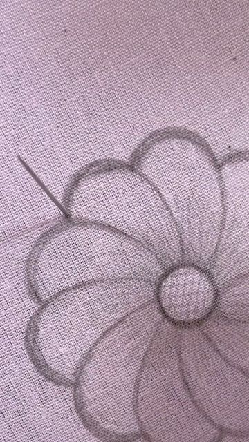 a drawing of a flower is shown on a piece of cloth with needles in it