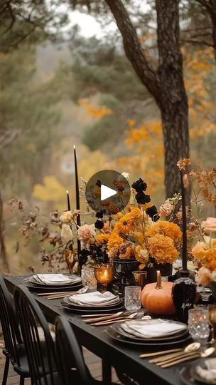 an outdoor table set with black and white place settings, gold candlesticks and flowers