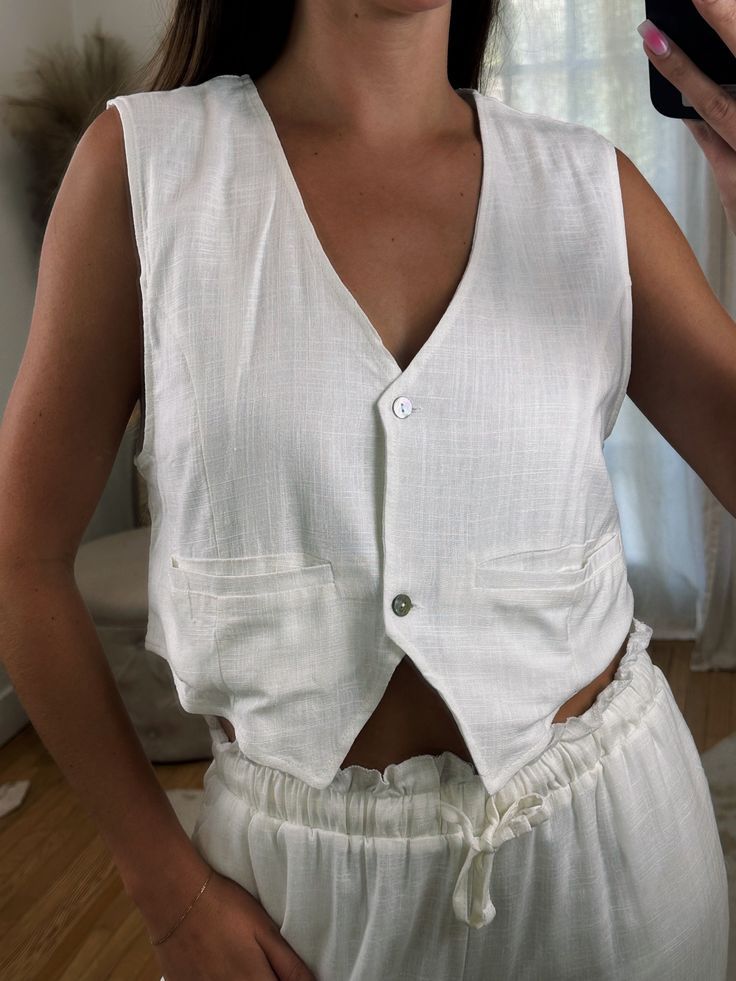 Our new linen vest top! Comes in White, Black and Brown. It features a looser fit, slightly cropped silhouette, and delicate button detailing. Look effortlessly chic by dressing it up with some jeans or pairing it with our Linen Love Pants for a complete matching linen fit!! Maclaine is 5'7 and wearing size Small. This is a looser fit! 70% Rayon 30% Linen Spring Linen Vest For Day Out, Spring Linen Beach Vest, Cropped Summer Vest With Pockets, Linen V-neck Vest For Day Out, Chic Linen Vest For Day Out, Casual Everyday Linen Vest, White Linen Casual Vest, Summer Cropped Vest With Buttons, Cropped Summer Vest With Buttons