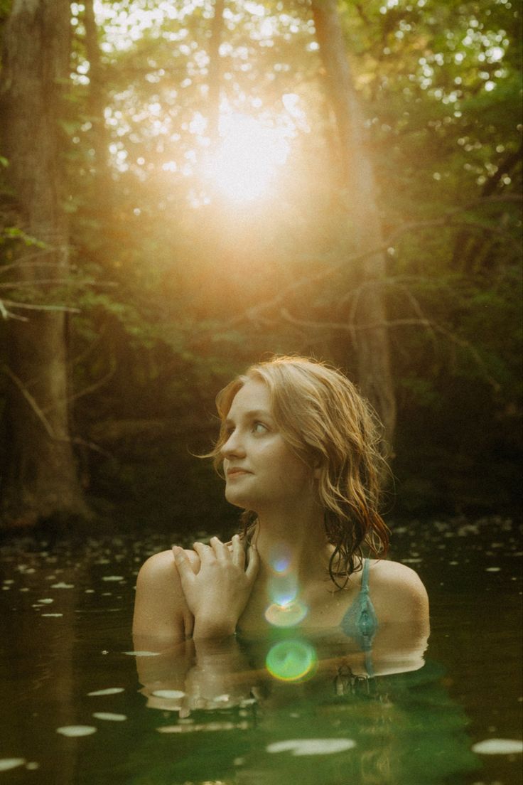 a woman is in the water with her hands on her chest and looking off into the distance