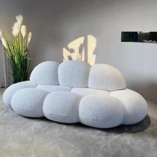 a white couch sitting on top of a carpet covered floor next to a potted plant