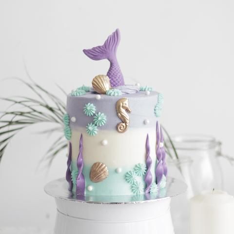 the cake is decorated with mermaids and seashells on it's sides