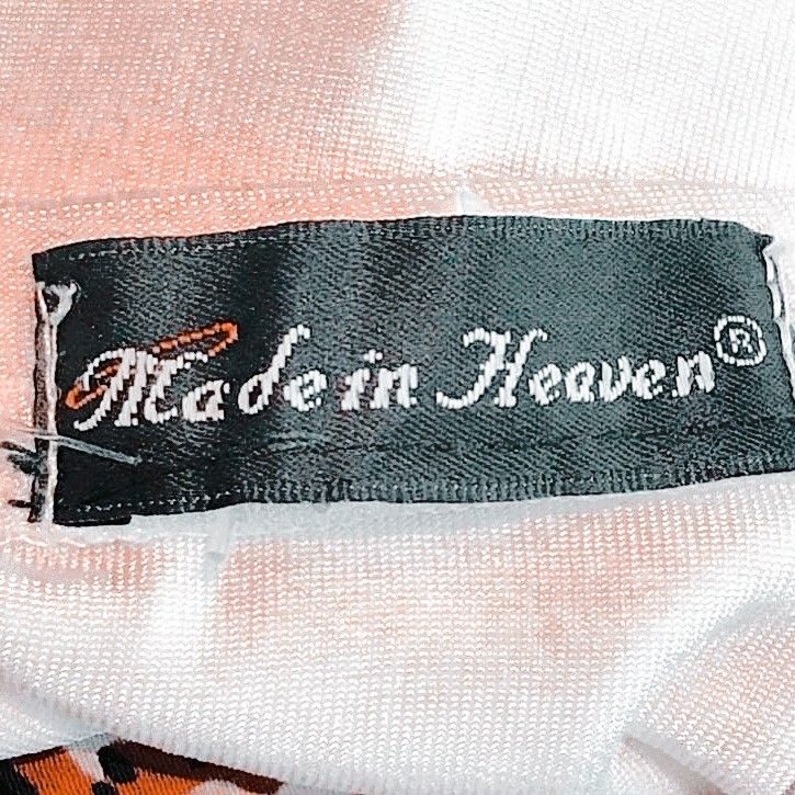 a label on the back of a white shirt that says made in heaven with an orange and black design