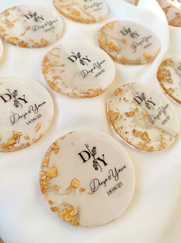 some cookies that have been decorated with gold flecks and writing on them are sitting on a white table cloth