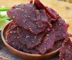 a wooden bowl filled with red meat on top of a table