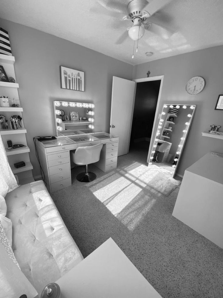 a black and white photo of a bedroom with lights on the ceiling, vanity mirror, desk and bed