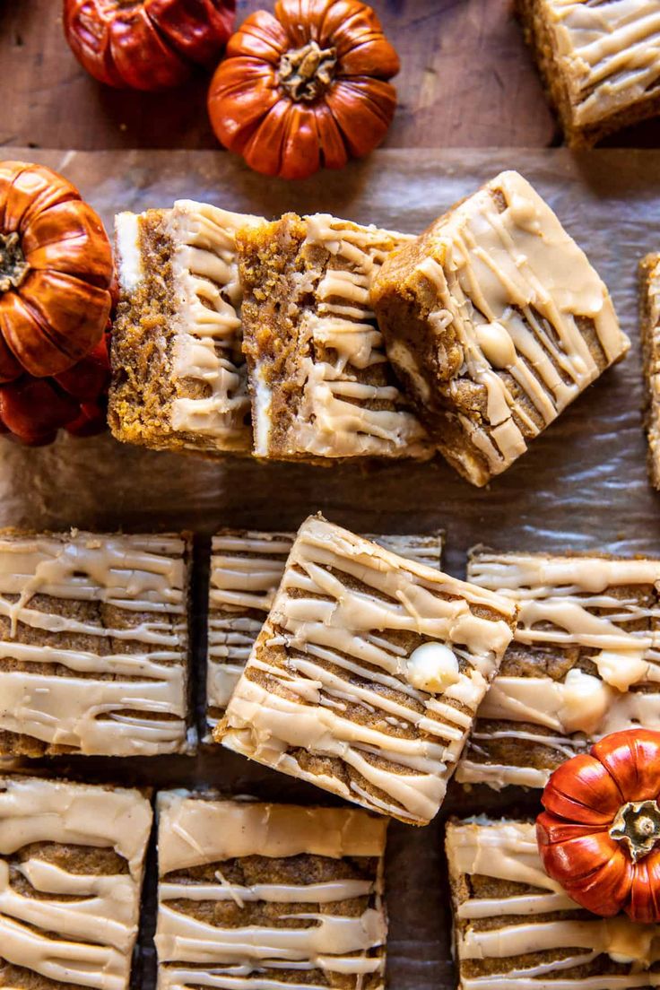 several slices of pumpkin spice cake on a wooden table with mini pumpkins around them